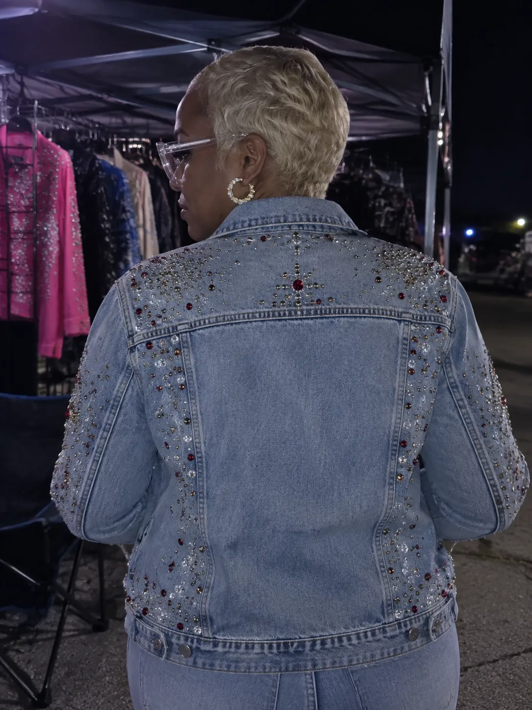 Back view of a crystal-studded embellished denim jacket shown in the booth at night
